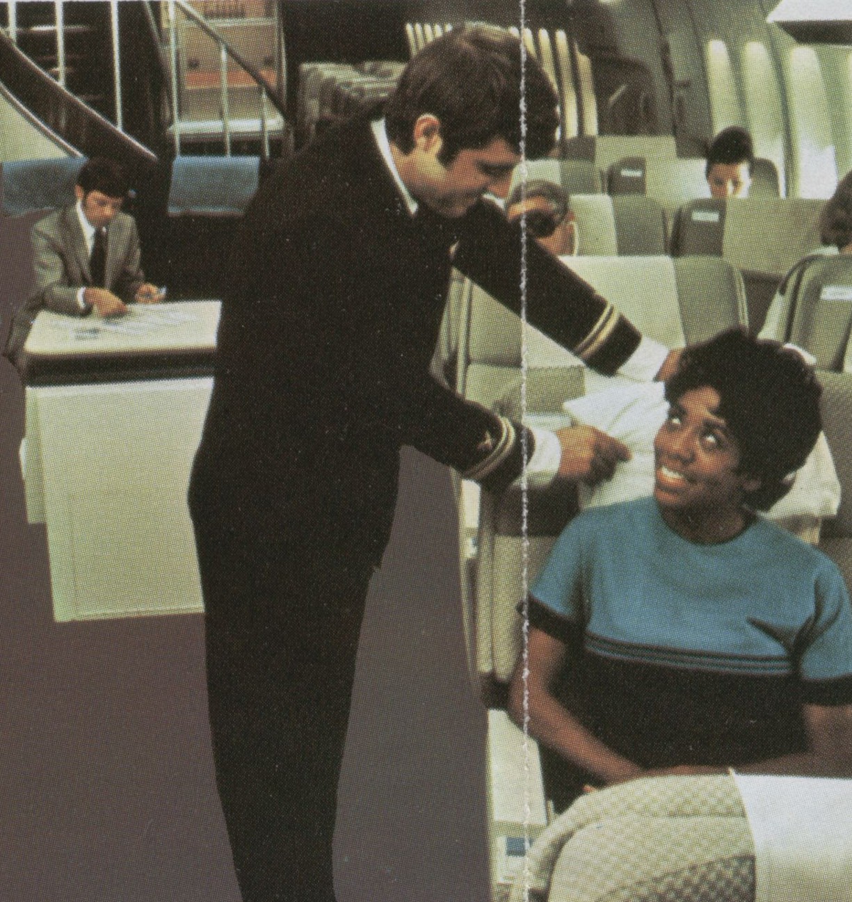 1970s  A Pan Am steward assists a customer in the First Class cabin of a Boeing 747.